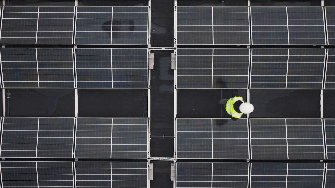 Top view of an engineer walking between rows of solar modules on a flat commercial rooftop